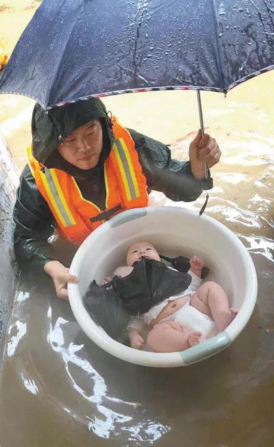 图为2020年6月27日,在宜昌市伍家岗区,消防员用水盆将3个月大的婴儿安全转移。 人民视觉 王方/摄